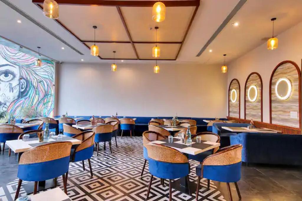 a restaurant with tables and chairs and a mural at The Grand Anukampa Oasis in Jaipur