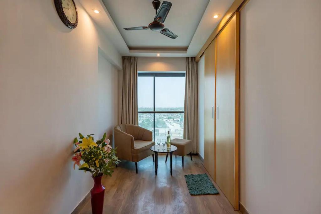 a living room with a table and a chair and a window at The Grand Anukampa Oasis in Jaipur lookinghotel