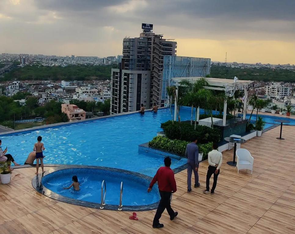 a group of people standing around a large swimming pool at The Grand Anukampa Oasis in Jaipur